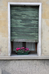 Fototapeta na wymiar window with blind of an old house with a balcony embellished wit