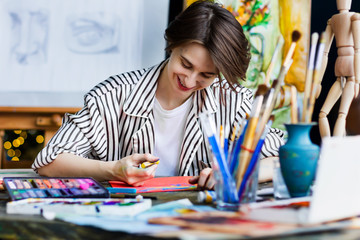 Young beautiful smiling artist teacher student woman girl boy in art workshop studio surrounded by...