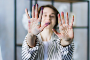 Young happy smiling beautiful artist teacher student woman girl boy in art workshop studio surrounded by black white art equipment tools gypsum busts show painted working hands just painted a picture