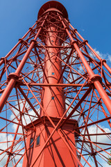 Red cast iron lighthouse against a blue sky