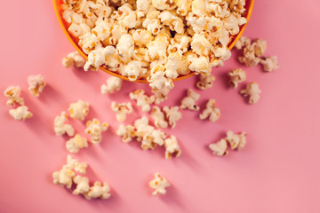 A bowl with popcorn on pink background.