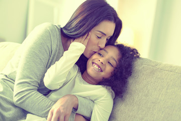 Beautiful caring woman kissing her daughter on the cheek.