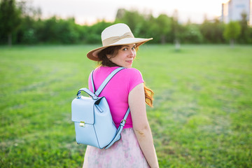 Summer and nature concept - Healthy smiling young woman walking on green grass with flowers.