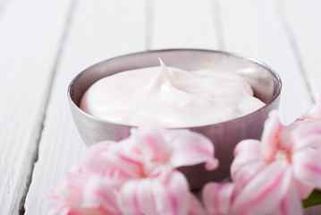 beauty and cosmetic creams with pink flowers on white wood