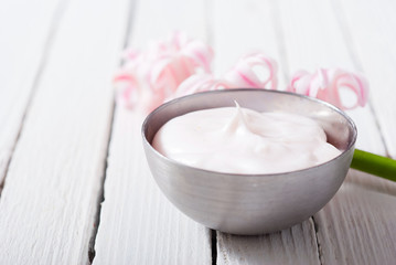 beauty and cosmetic creams with pink flowers on white wood