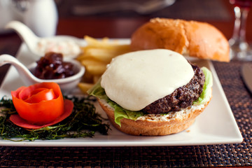 Large tasty burger with French fries in a cafe on a white plate. Food concept
