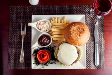 Large tasty burger with French fries in a cafe on a white plate. Food concept