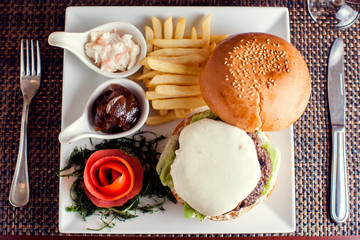 Large tasty burger with French fries in a cafe on a white plate. Food concept