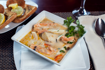 Seafood cream soup with toasts in white plate on the table. Food and restaurant concept