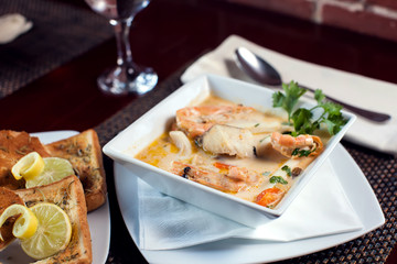 Seafood cream soup with toasts in white plate on the table. Food and restaurant concept