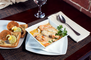 Seafood cream soup with toasts in white plate on the table. Food and restaurant concept