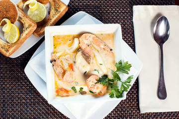 Seafood cream soup with toasts in white plate on the table. Food and restaurant concept