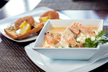 Seafood cream soup with toasts in white plate on the table. Food and restaurant concept