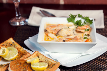 Seafood cream soup with toasts in white plate on the table. Food and restaurant concept