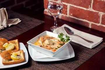 Seafood cream soup with toasts in white plate on the table. Food and restaurant concept