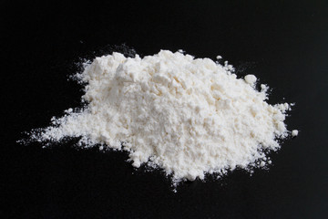 Fototapeta na wymiar white flour on a black background in a handful