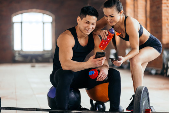 happy fit couple looking fot the Net at gym. young people brousing the net during rest in the sport club