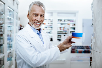 Bearded handsome man with facial wrinkles showing new medicine