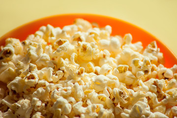 An orange bowl with popcorn isolated on yellow background