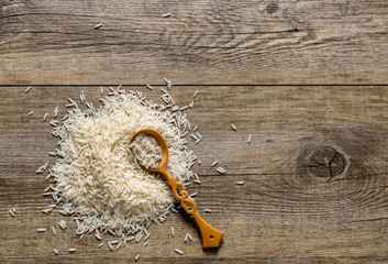 Top view of Basmati Rice pile with wooden spoon on the antique wooden background. 