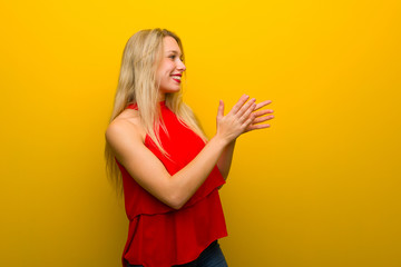 Young girl with red dress over yellow wall applauding after presentation in a conference