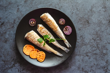 Fried hake served with sweet potatoes and red onion.
