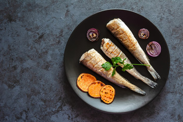 Fried hake served with sweet potatoes and red onion.