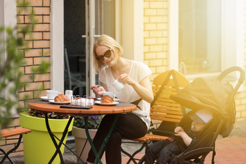 Young mother with her one-year-old child in a street cafe