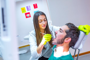 Doctor doing dental treatment on man's teeth in the dentists chair.