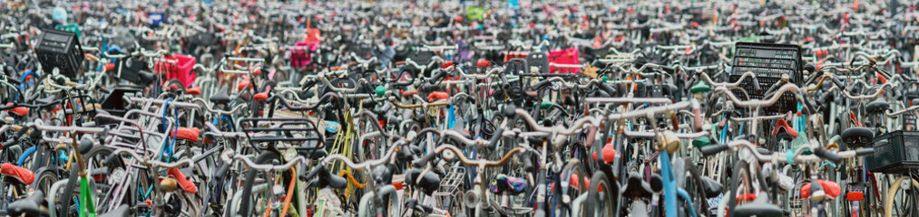 Panoramic view of a huge crowded public bicycle parking with many children seats.