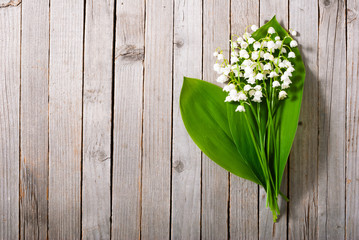 bouquet of lily of the valley on old weathered wooden table background