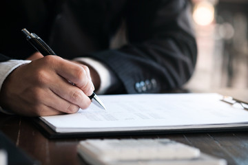 Businessman analyzing investment charts and pressing calculator buttons over documents. Accounting Concept.