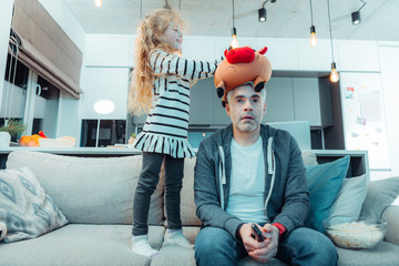 Cute long-haired girl in a dress playing with her father