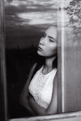 girl by the window in a wooden house with dim light black and white colors