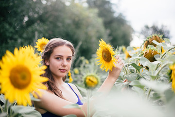 Beautiful girl on the field with sunflowers in short shorts and a vest