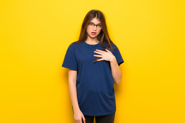 Young woman with glasses over yellow wall surprised and shocked while looking right