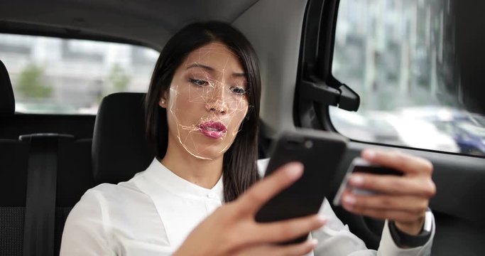 Business Woman in car using facial recognition technology to unlock smart phone and make payment
