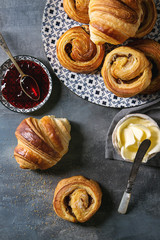 Variety of homemade puff pastry buns cinnamon rolls and croissant served with jam, butter as...