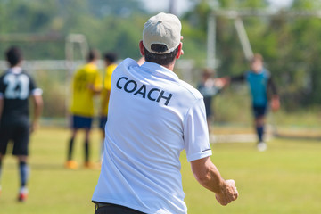 Fototapeta premium Back of sport coach wearing COACH shirt at an outdoor sport field
