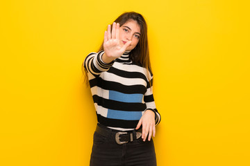 Young woman over yellow wall making stop gesture denying a situation that thinks wrong