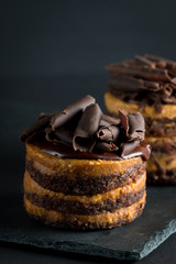Chocolate cakes on black slatter board with mint, coffee beans on dark background, closeup photo. Fresh, tasty dessert food concept. 