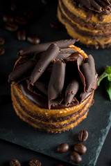 Chocolate cakes on black slatter board with mint, coffee beans on dark background, closeup photo. Fresh, tasty dessert food concept. 