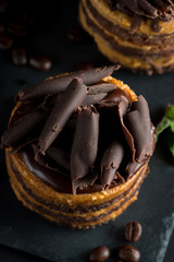 Chocolate cakes on black slatter board with mint, coffee beans on dark background, closeup photo. Fresh, tasty dessert food concept. 