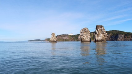 View of Tri Brata with Koryaksky volcano's top in the background. Tri Brata (Russian: Три Брата; literally: "three brothers") is a set of three rocks at the entrance to the Avacha Bay.