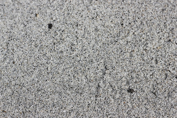 Light brown sand texture with black dots on the beach of Lake Baikal. Dotted beige sandy floor with blurred part for summer vacation background with place for text