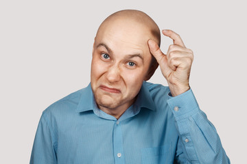 a bald guy shows a hand gesture meaning a very small amount of something