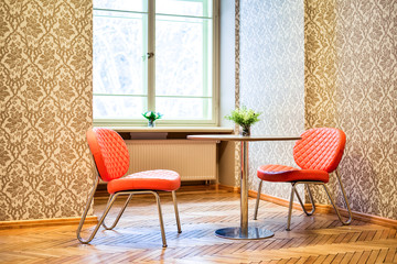 Cafeteria with two comfortable red chairs and a metal table. Beautiful unusual interior in the room