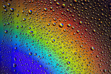 Drops of water on the glass, with the reflection of the rainbow.