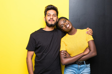 Young happy mixed race couple indian man and african woman hug isolated on yellow black background