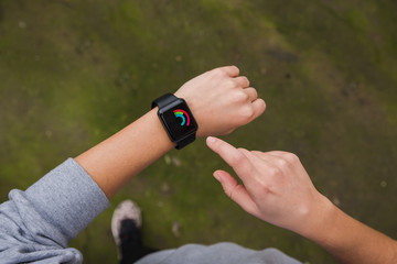 Close up of young woman checking the smartwatch device, outdoors.